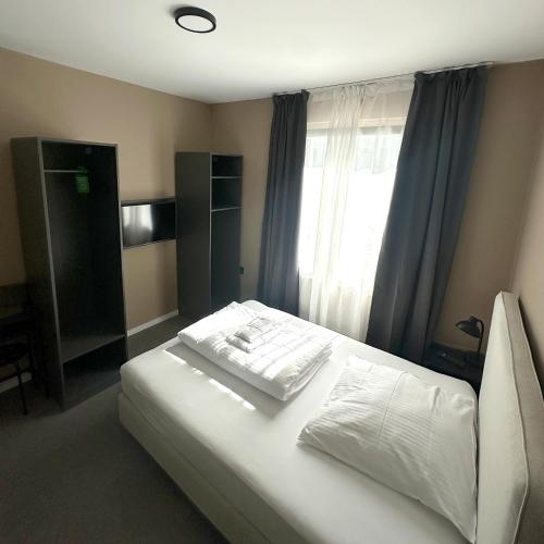 a bedroom with a white bed with a window at Benztown Hotel Gästehaus in Stuttgart