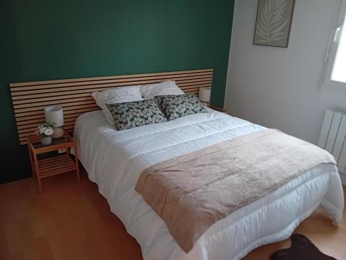 - un grand lit dans une chambre dotée d'un mur vert dans l'établissement agathe&compagnie, à La Celle-sous-Gouzon