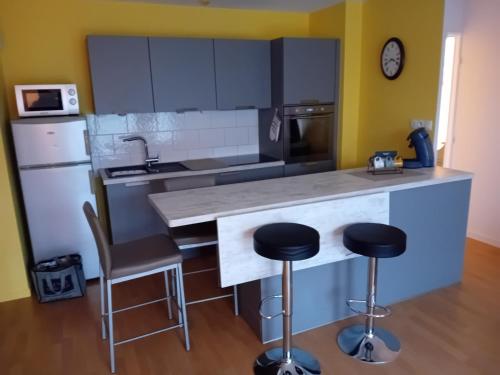 une cuisine avec un comptoir et deux tabourets de bar dans l'établissement agathe&compagnie, à La Celle-sous-Gouzon