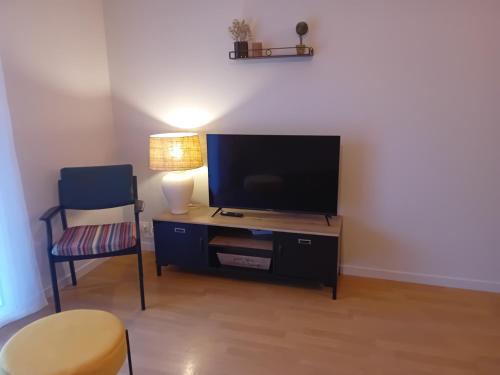 un salon avec une télévision et une chaise dans l'établissement agathe&compagnie, à La Celle-sous-Gouzon