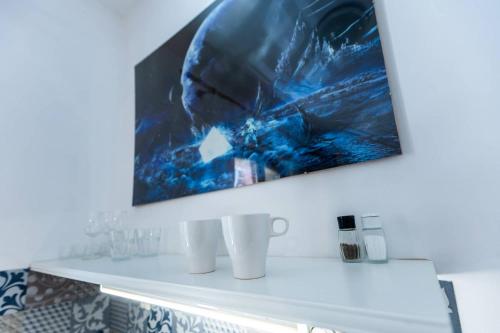 a painting hangs above a white shelf in a bathroom at Planetarium - Stare Miasto, Parking Free in Toruń