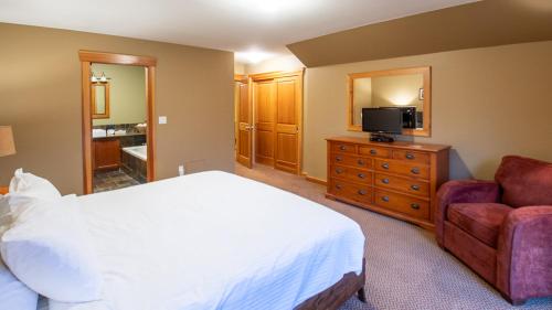 a bedroom with a bed and a tv and a couch at Pinnacle Ridge Chalets by Fernie Lodging Co in Fernie