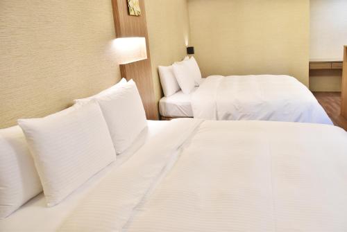 two beds in a hotel room with white sheets and pillows at Innk in Taichung