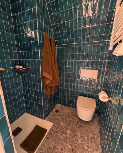La salle de bains est pourvue de toilettes et d'un mur carrelé vert. dans l'établissement CaBaNa 52 La Suite troglodyte Proche Lourmarin, à Cadenet