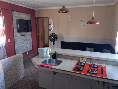 a kitchen with a sink and a red stove at Casa Água da Rocha in Itaguaí