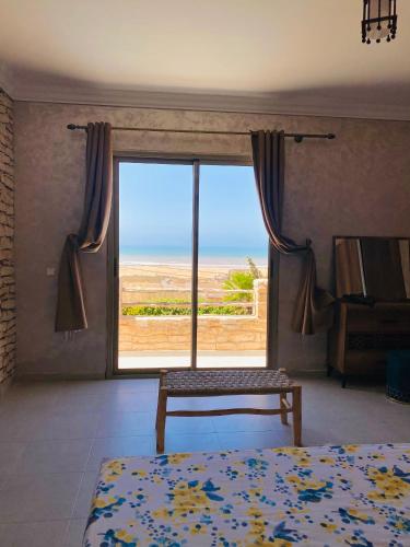 a bedroom with a large window with a view of the beach at Villa Sunset Moulay Bouzerktoun in Essaouira