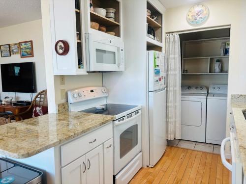 a kitchen with white cabinets and white appliances at Serenity Now in Holden Beach