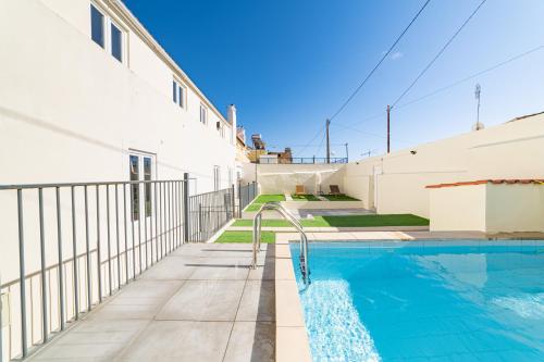 a swimming pool next to a white building at Vila Lopes in Lisbon