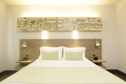 a bedroom with a large white bed with two pillows at Hotel bh Usaquén in Bogotá