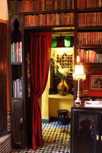 a library with a red curtain and a room with books at Riad Le Calife in Fès