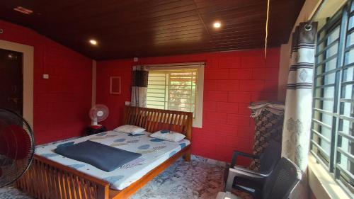 a red room with a bed in a red wall at Homestay Nandana 2nd floor in Gokarna