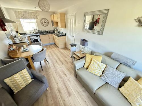 a living room with a couch and a table at Dudleys Retreat - Part of the The Bay Filey Holiday Village with pool, gym and direct beach access, pub, restaurant, tennis and meadows walks in Filey
