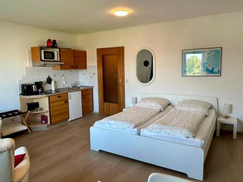 ein Schlafzimmer mit einem weißen Bett und einer Küche in der Unterkunft Haus Elbe -Wohnung 14- Zentral in Döse in Cuxhaven