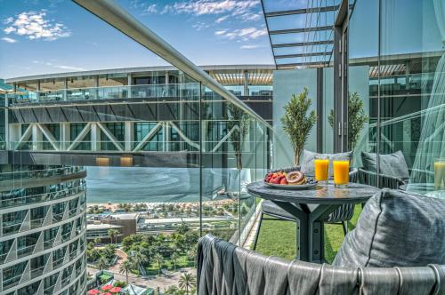 a balcony with a table with a bowl of fruit and orange juice at Palm Jumeirah - Luxe Infinity Pool I Direct Beach Access in Dubai