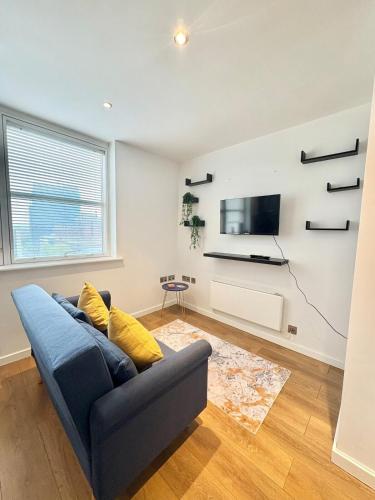 a living room with a blue couch and a tv at Cosy Flat Leeds City Centre in Central Station