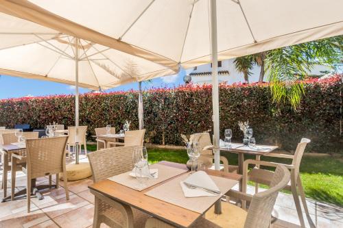 a patio with tables and chairs with umbrellas at Hotel Rural Brícia Du Mar in Ferragudo