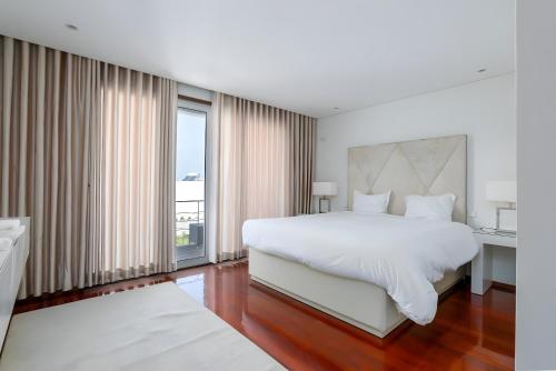 a bedroom with a large bed and a large window at The Povoa Villa in Póvoa de Varzim