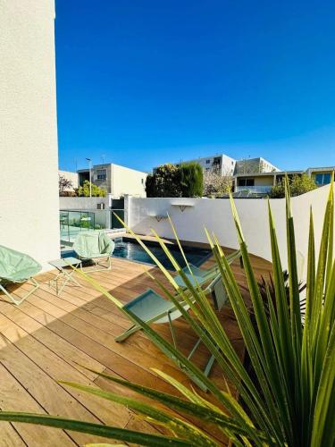une vue d'une terrasse en bois avec une piscine sur un immeuble dans l'établissement Villa calme avec piscine, Montpellier city center, à Montpellier