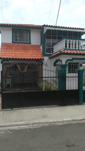 a fence in front of a house with a building at Queen Bmazazhi Stay in San Pedro de Macorís