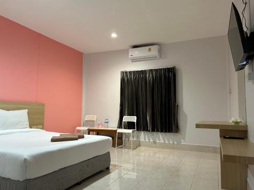 a bedroom with a white bed and a pink wall at Hatyai Bangkok Resort หาดใหญ่ บางกอก รีสอร์ท in Hat Yai