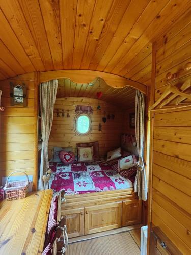 une chambre avec un lit dans une cabane en bois dans l'établissement Roulotte Gentiane, à Gèdre