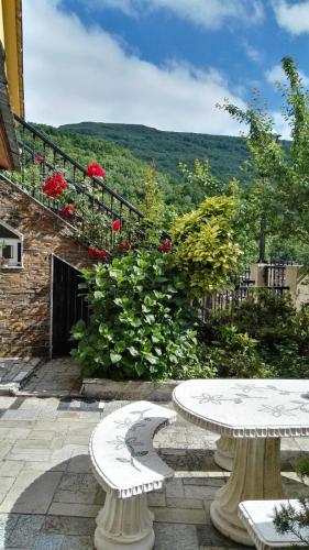 two white benches sitting on a patio with flowers at Casa David in Tríacastela