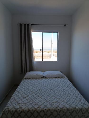 a bedroom with a bed and a window at Relaxe à Beira-Mar com pé na areia! in Tramandaí