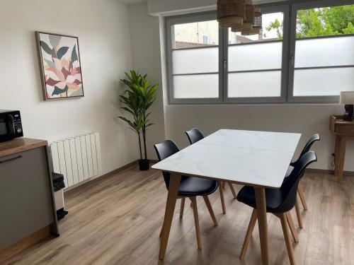 a white table and chairs in a room with windows at L Etape Châtillonnaise center private parking in Châtillon-sur-Chalaronne