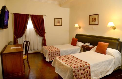 a hotel room with two beds and a desk at Hotel Muñiz in Bahía Blanca