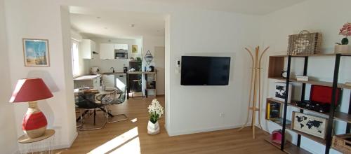 un salon avec une télévision et un salon avec une table dans l'établissement Maison duplex Bisca avec jardin, à Biscarrosse