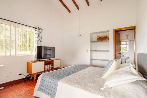 a white bedroom with a bed and a tv at Casa en Cerritos con Piscina y 4 habitaciones in Pereira