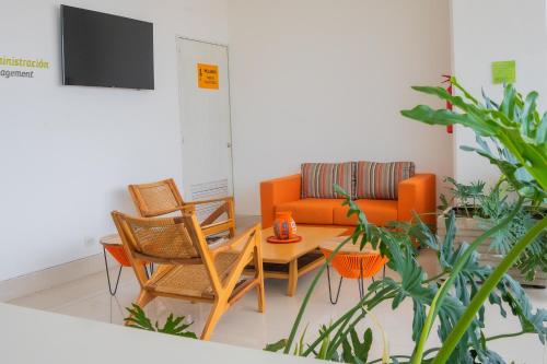 a living room with an orange couch and chairs at Mia Hotel Choco in Quibdó