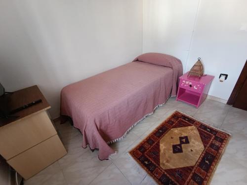 a bedroom with a bed and a table and a rug at Habitación tranquila con acceso a Barbacoa y piscina in Pobla de Montornés