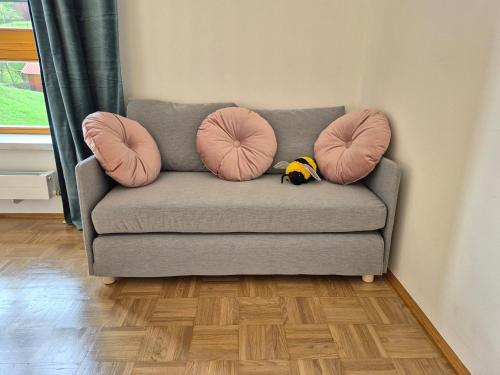 a gray couch with two pink pillows on it at appartement bumblebee in Sankt Lambrecht