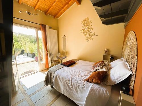 a bedroom with a bed and a large window at Maison d'Hotes du Vert Vallon in Theizé