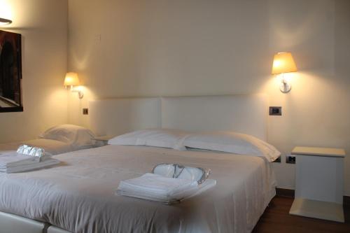 a bedroom with two beds with white sheets and towels at Il Borgo Ospitale - Albergo Diffuso in Rotonda
