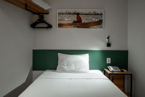 a bedroom with a white bed and a green wall at ibis Styles Belem Nazare in Belém
