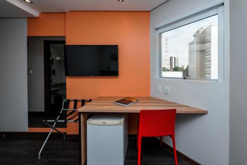 a dining room with a table and a tv on a wall at ibis Styles Belem Nazare in Belém