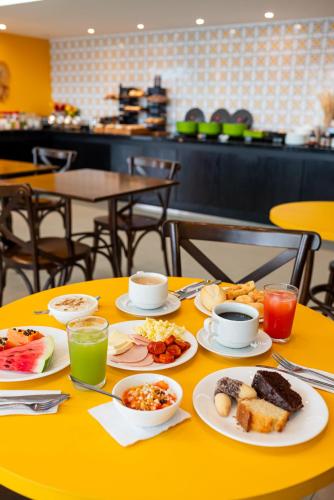 a yellow table with plates of breakfast food on it at ibis Styles Belem Nazare in Belém