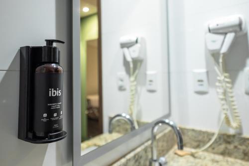 a bathroom mirror with a bottle of hair dryer on a sink at ibis Styles Belem Nazare in Belém