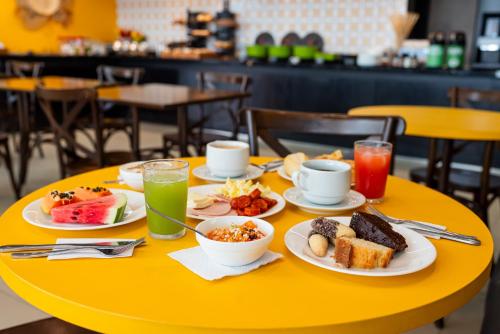 a yellow table with plates of breakfast food on it at ibis Styles Belem Nazare in Belém