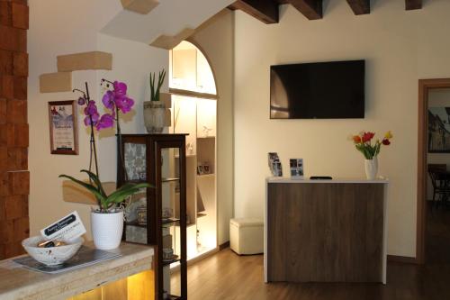 a living room with a tv and flowers on a counter at Il Borgo Ospitale - Albergo Diffuso in Rotonda