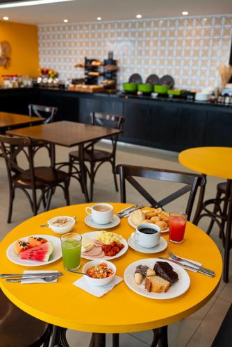 a yellow table with plates of food on it at ibis Styles Belem Nazare in Belém