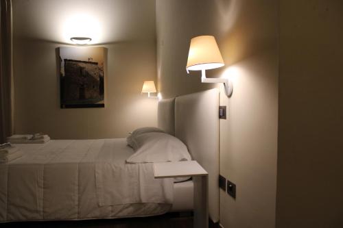 a bedroom with a bed and two lights on the wall at Il Borgo Ospitale - Albergo Diffuso in Rotonda