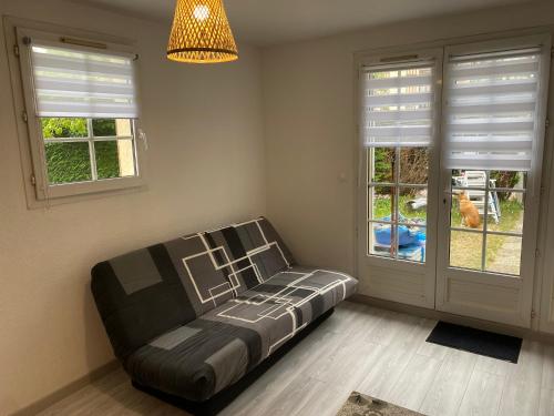 - un canapé dans une chambre avec 2 fenêtres dans l'établissement Cottage Normand avec jardin de 80 m2, à Villers-sur-Mer
