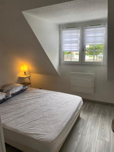 une chambre blanche avec un lit et deux fenêtres dans l'établissement Cottage Normand avec jardin de 80 m2, à Villers-sur-Mer
