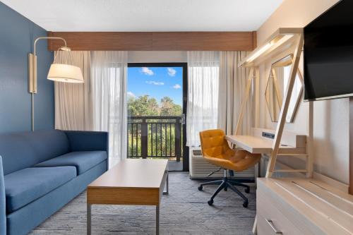 a living room with a blue couch and a desk at Holiday Inn Express Hilton Head Island by IHG in Hilton Head Island