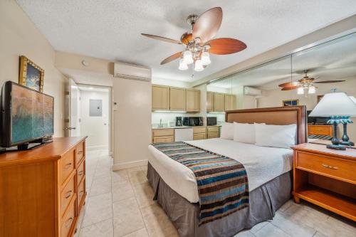 a bedroom with a bed and a flat screen tv at Kahana Falls Resort in Honokowai