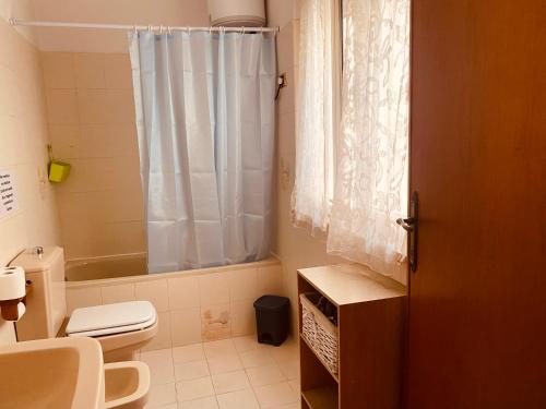 a bathroom with a toilet and a shower curtain at Mary's House in Iglesias