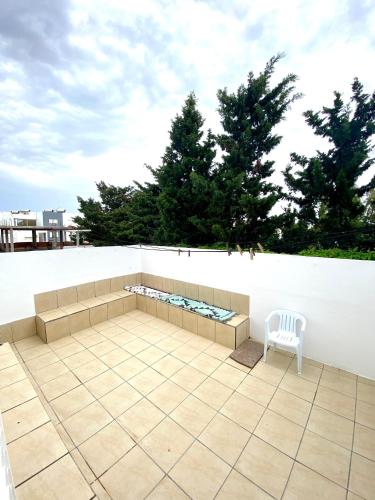 a white chair sitting on a patio next to a white wall at Duplex El mansoura A1 in Kelibia
